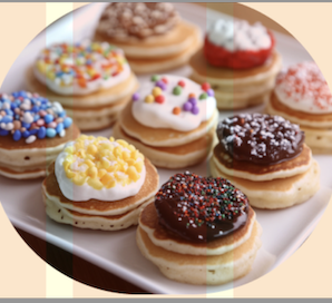 A plate of mini fluffy pancakes topped with colorful sprinkles, whipped cream, and fresh fruits, made to delight kids.