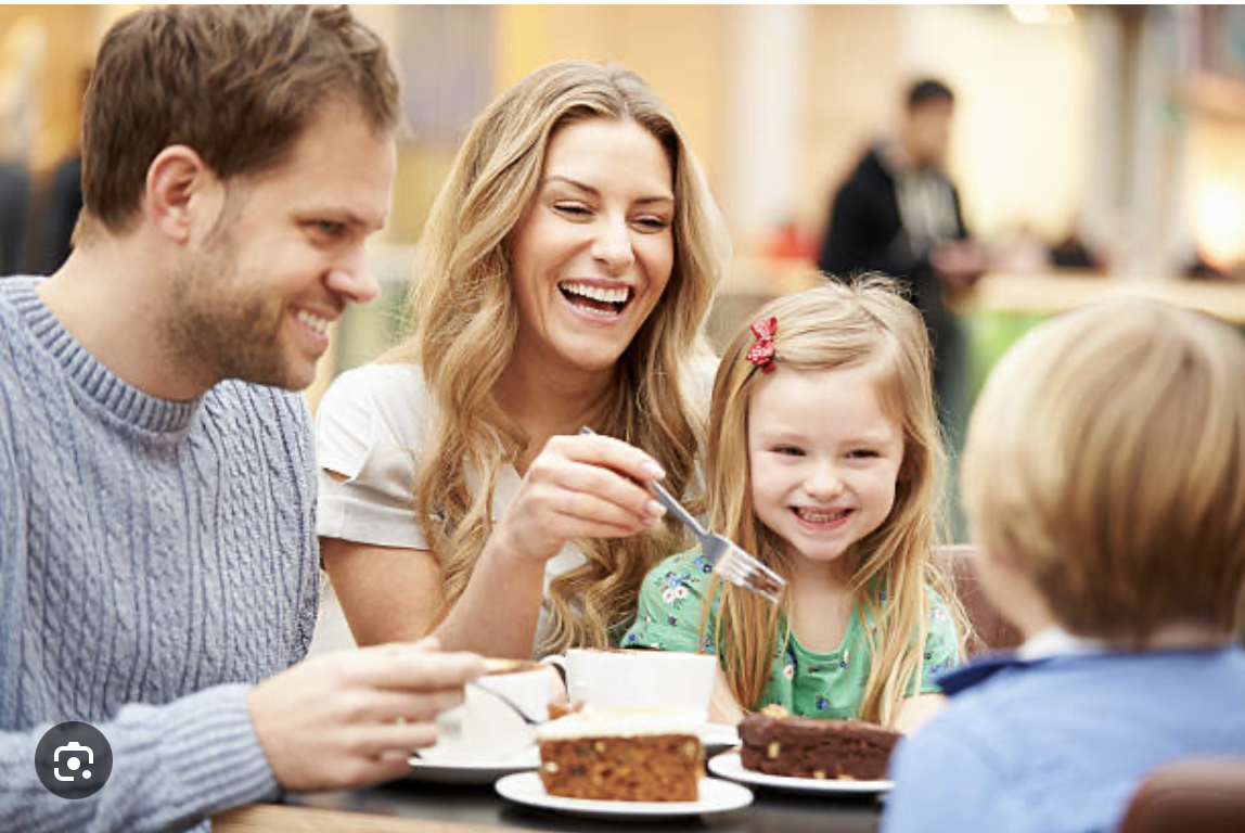 A happy family of four enjoying coffee and desserts.